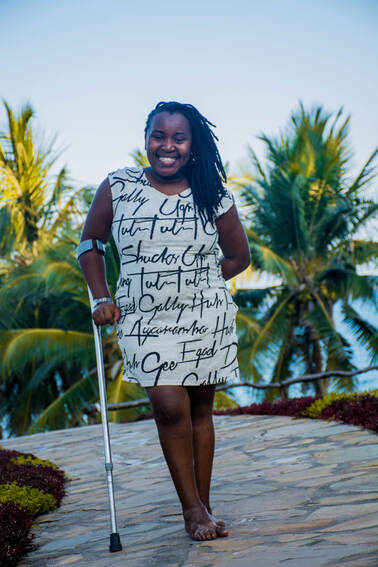 Young black woman standing outside with a crutch