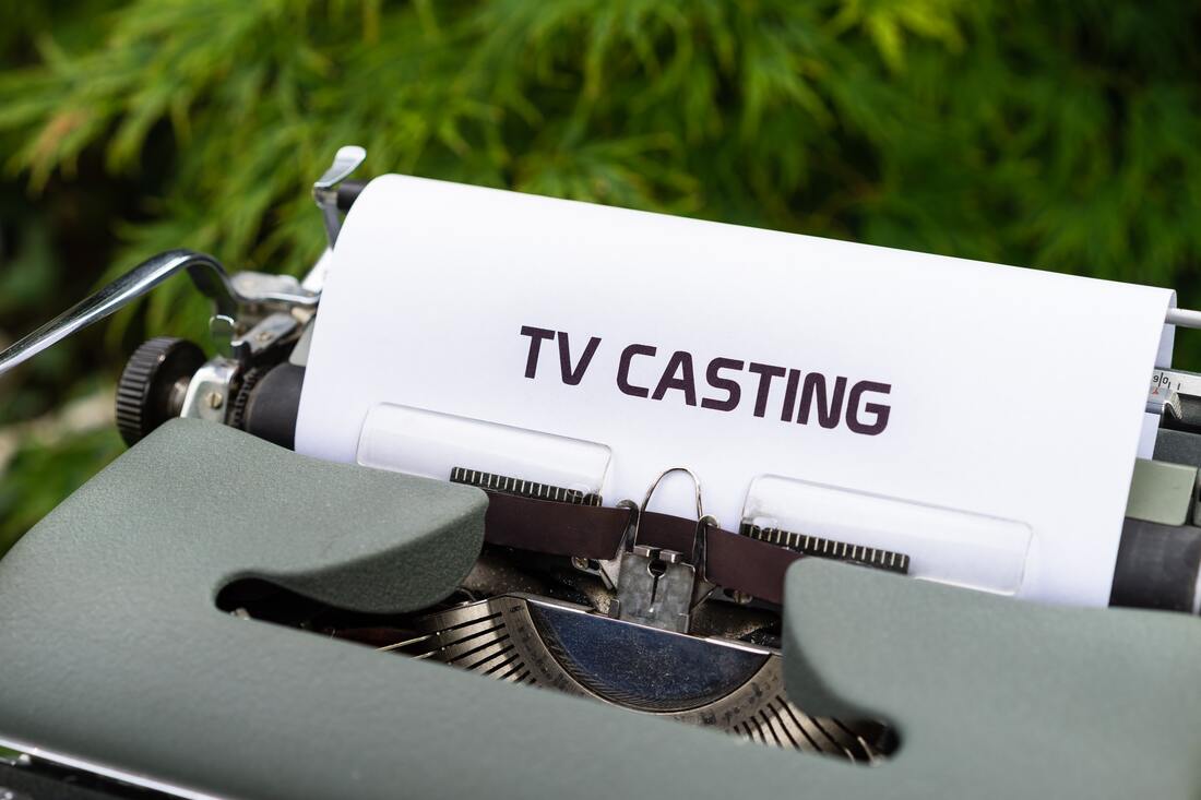 The image shows a typewriter with a sheet of paper. The words TV Casting is written on the paper.